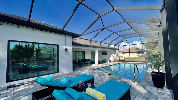 Zona de piscina exterior cubierta con sillas de descanso y un área de estar.