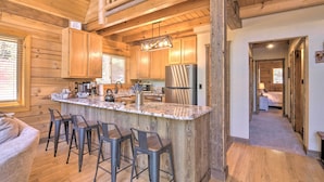 A spacious kitchen with wooden cabinets, a large island with bar stools, and a modern refrigerator. - Walk to Duck Creek Village: A-Frame Getaway! (Duck Creek Village)