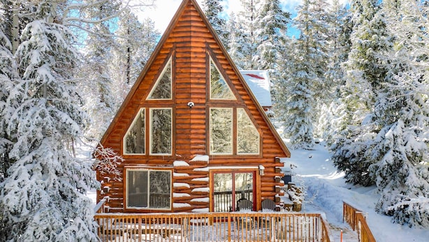 A log cabin with a triangular roof, large windows, and a wooden deck. - Walk to Duck Creek Village: A-Frame Getaway! (Duck Creek Village)