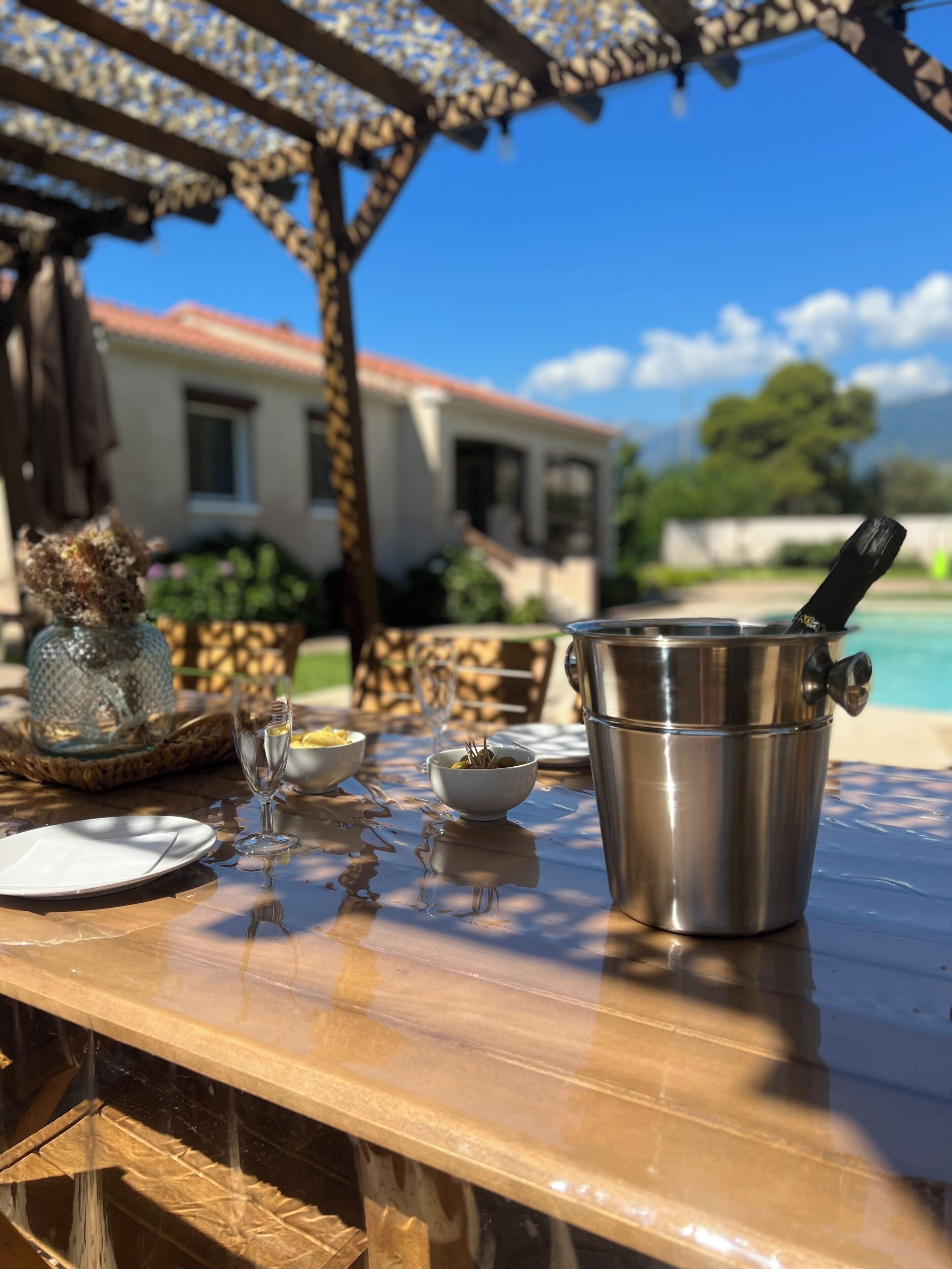 A dining table with a metal bucket, a glass, and a bowl of olives.