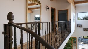 Una escalera con barandillas de metal decoradas y techo de madera.