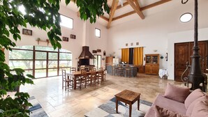 Amplia sala de estar con una mesa de comedor de madera, un sofá y una cocina al fondo.