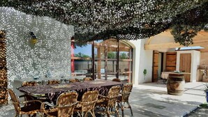 Un área de comedor al aire libre con una mesa y sillas, rodeada por un muro decorativo y una pérgola.