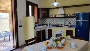 A kitchen with a dining area, a refrigerator, a stove, and a sink. - Arimondi cottage with patio and garden (San Vito Lo Capo)