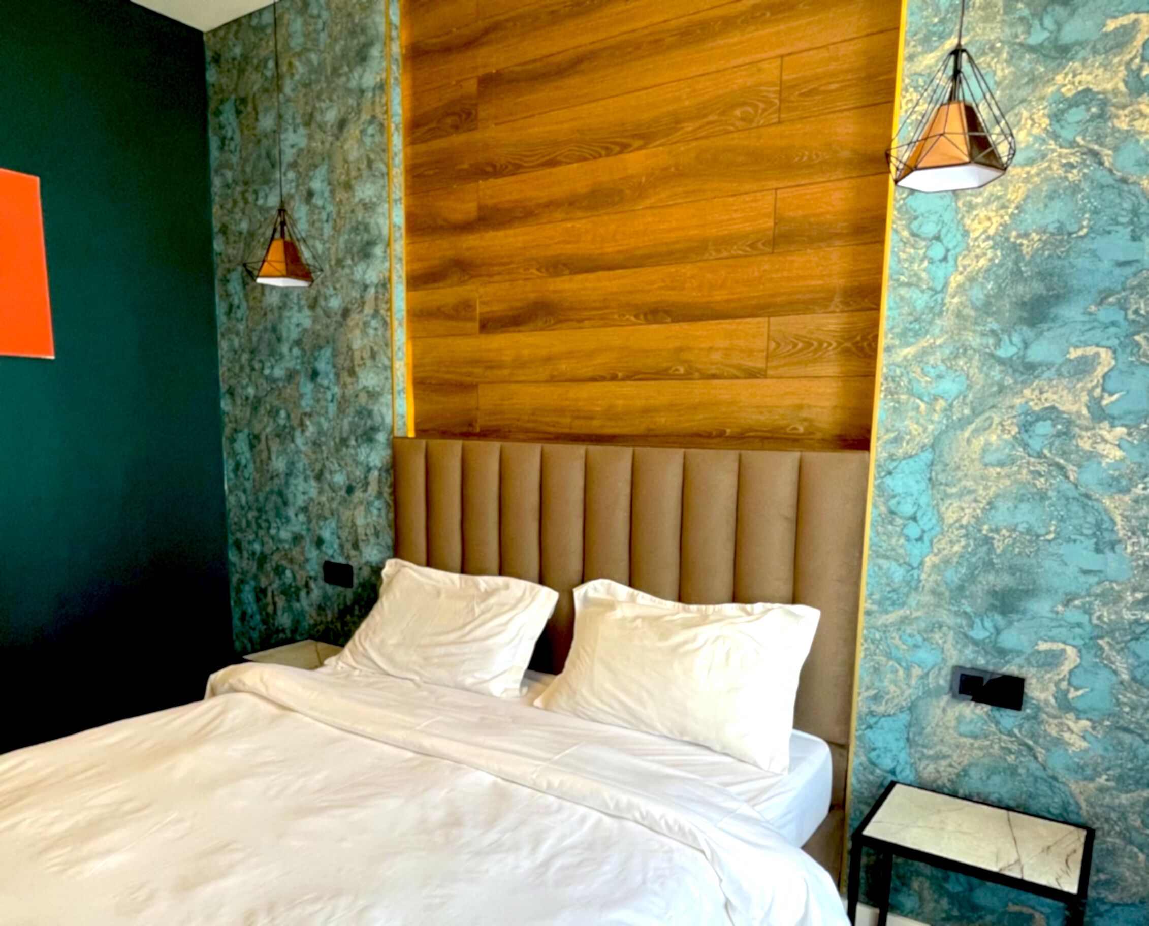A bed with white linens, a wooden headboard, and two bedside lamps.
