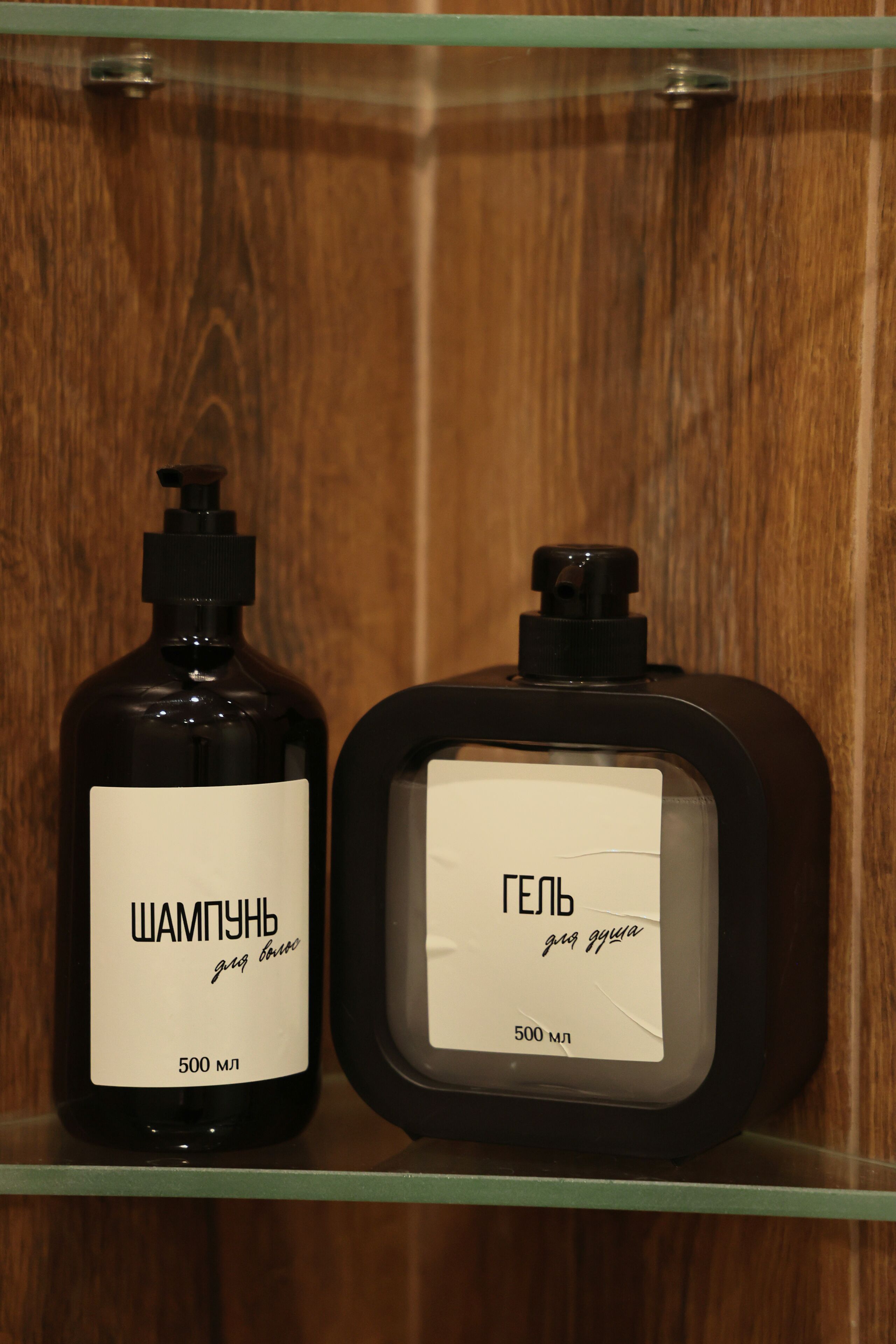 Deux bouteilles, dont les étiquettes sont visibles, sont posées sur une étagère devant un fond en bois.