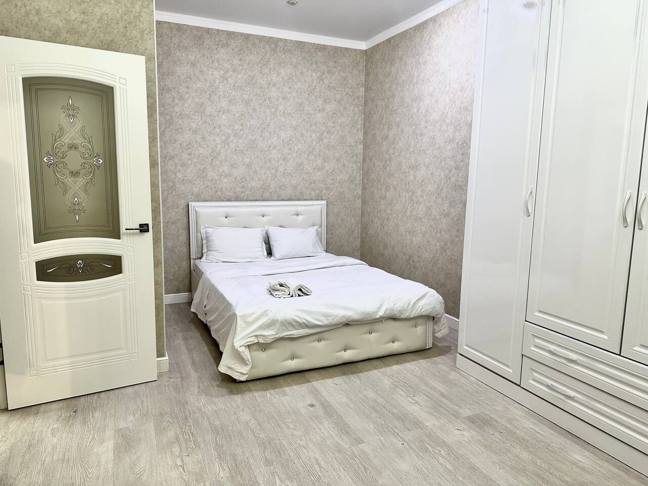 A bedroom with a bed, wardrobe, and a door with decorative paneling.