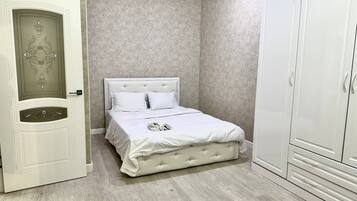 A bedroom with a bed, wardrobe, and a door with decorative paneling.
