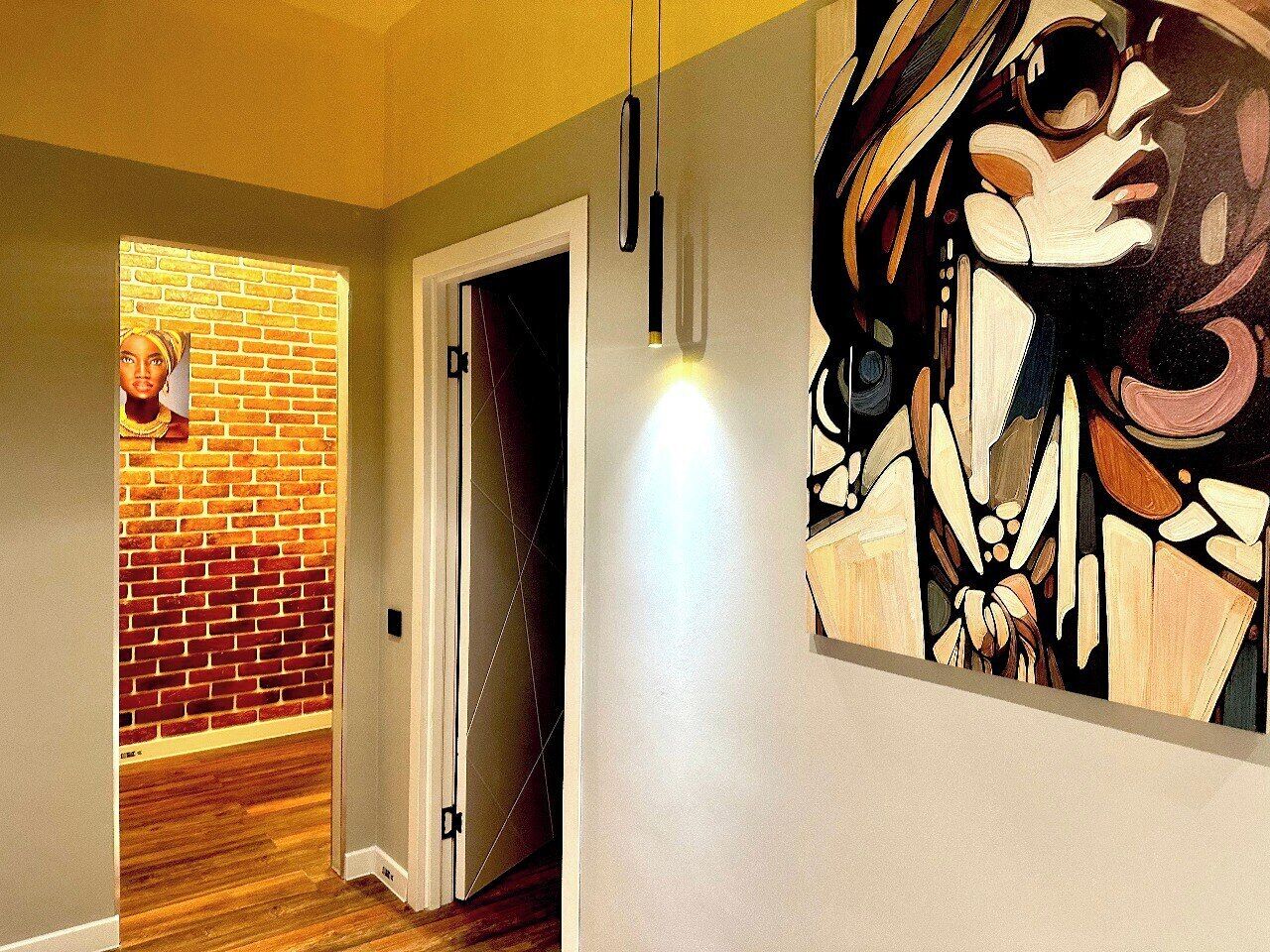 Un couloir avec un mur en briques, un plancher en bois et un tableau accroché au mur.