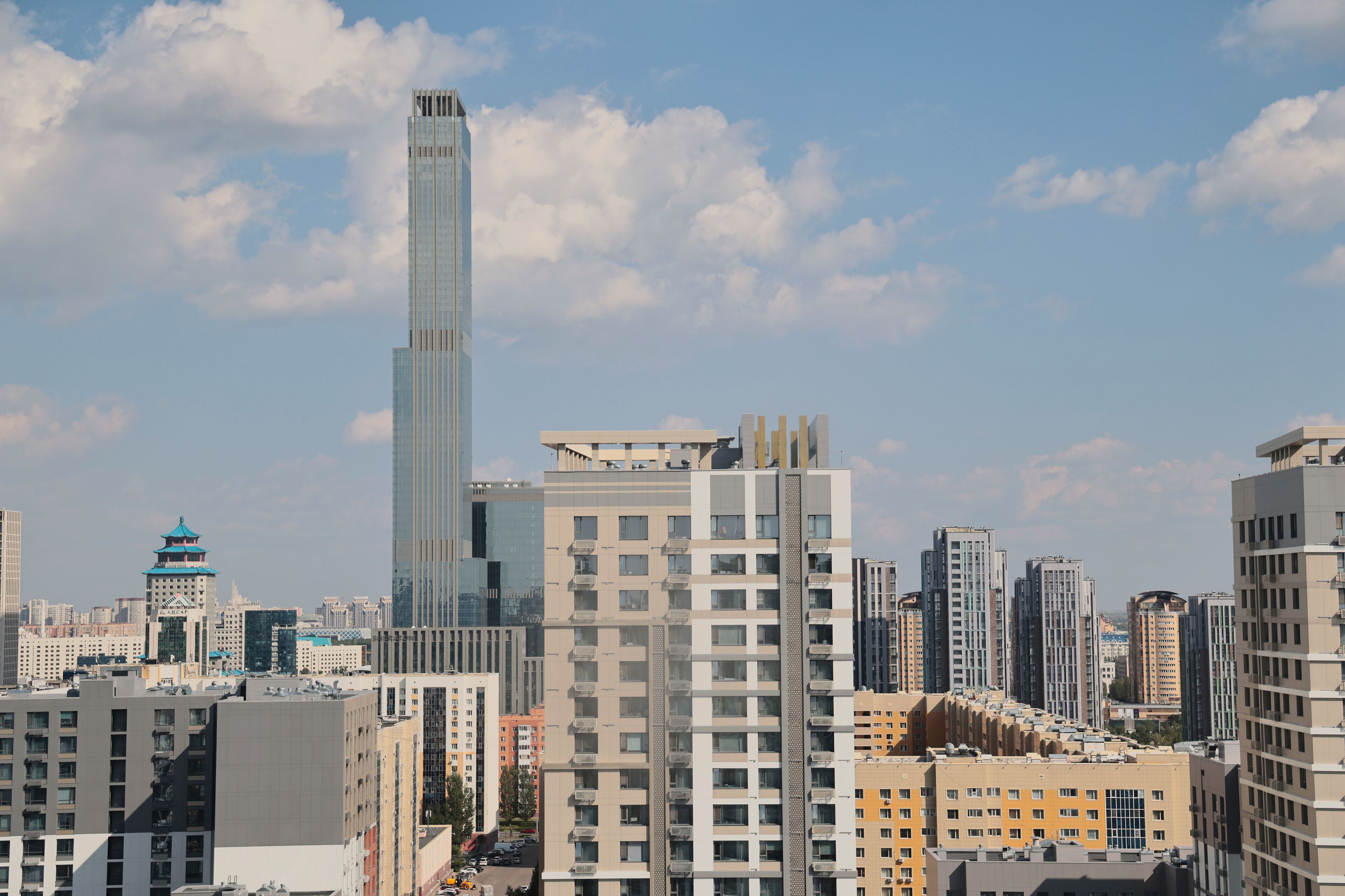 A high-rise building with a modern design, surrounded by other residential and commercial structures.