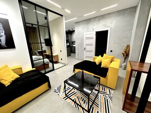 A modern hotel room with a sofa, a coffee table, and a dining area. - Prego apartments Almatau (Astana)
