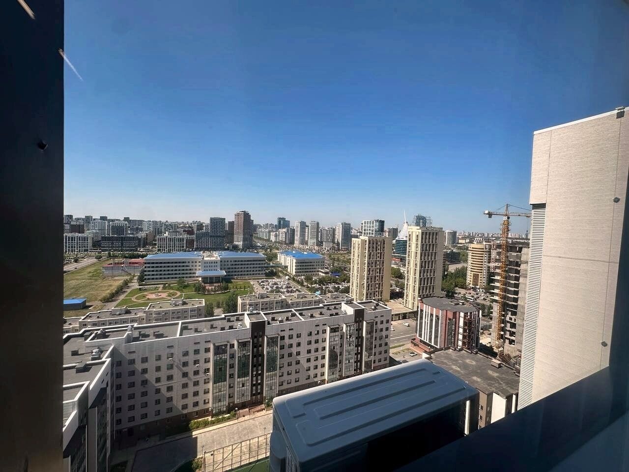 Un edificio de gran altura con varios pisos, ventanas amplias y vistas a un paisaje urbano con diversos edificios y un cielo despejado.