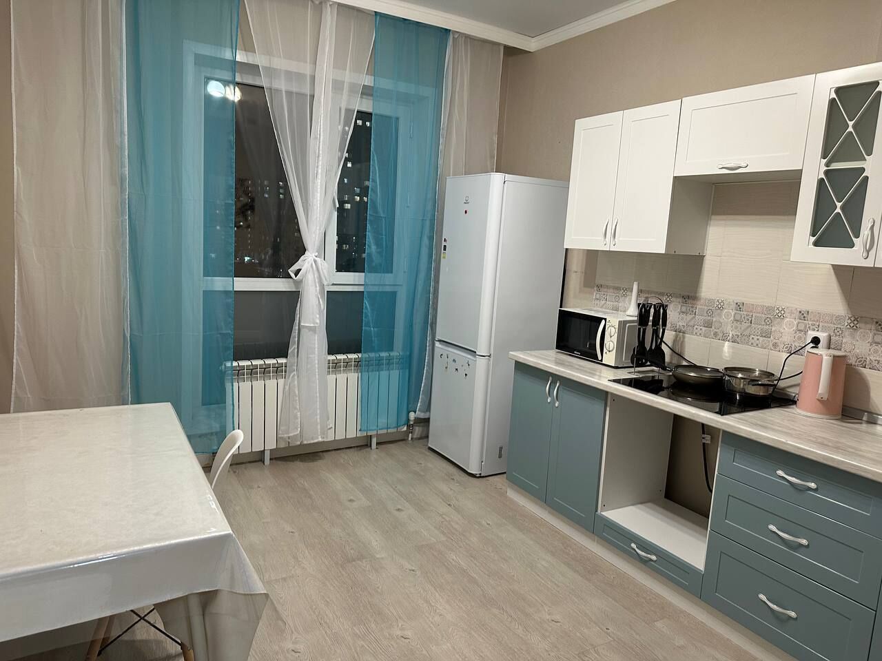 A compact kitchen with a refrigerator, stove, and cabinets.