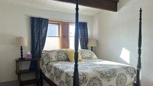 Un lit à baldaquin avec une couvre-lit à motifs, deux tables de chevet avec des lampes et une fenêtre avec des rideaux.