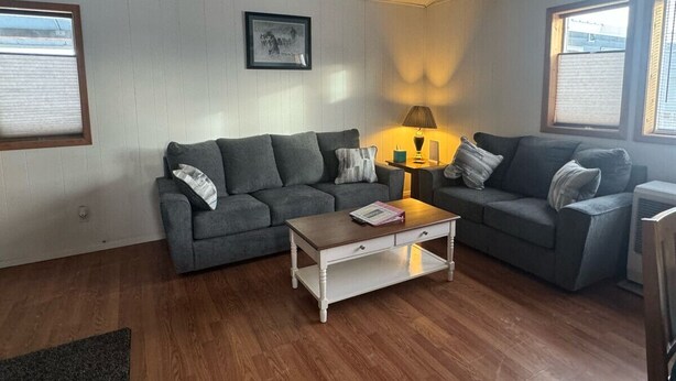 Un salon avec deux canapés gris, une table basse en bois et une lampe.