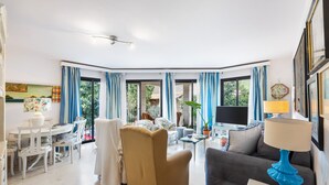 A modern living room with a dining area, large windows with curtains, and a blue lamp. - Stunning Apartment "Ca Na Bel" with Private Terrace, Balcony & Wi-Fi (Port de Sóller)