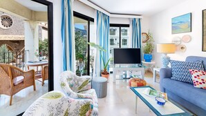 A modern living room with a sofa, armchair, TV, and dining area. - Stunning Apartment "Ca Na Bel" with Private Terrace, Balcony & Wi-Fi (Port de Sóller)