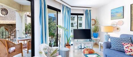 A modern living room with a sofa, armchair, TV, and dining area.