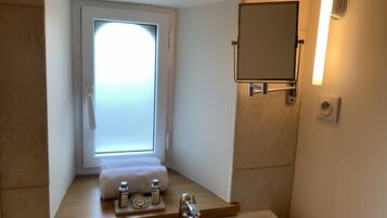 Een moderne badkamer met een ingebouwd raam, een spiegel en een wastafel met toiletartikelen.