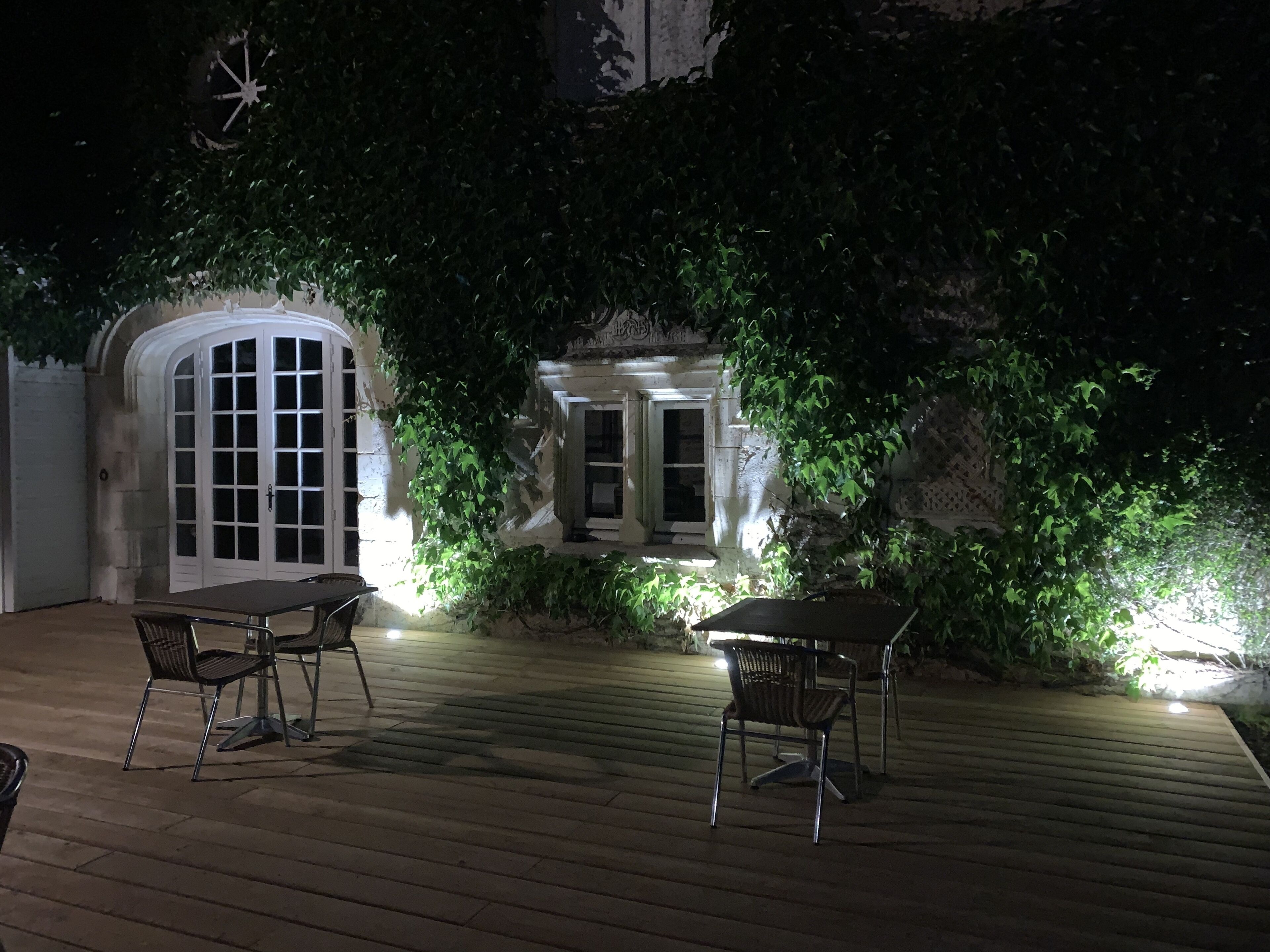 Un patio al aire libre con suelo de madera y dos mesas con sillas.