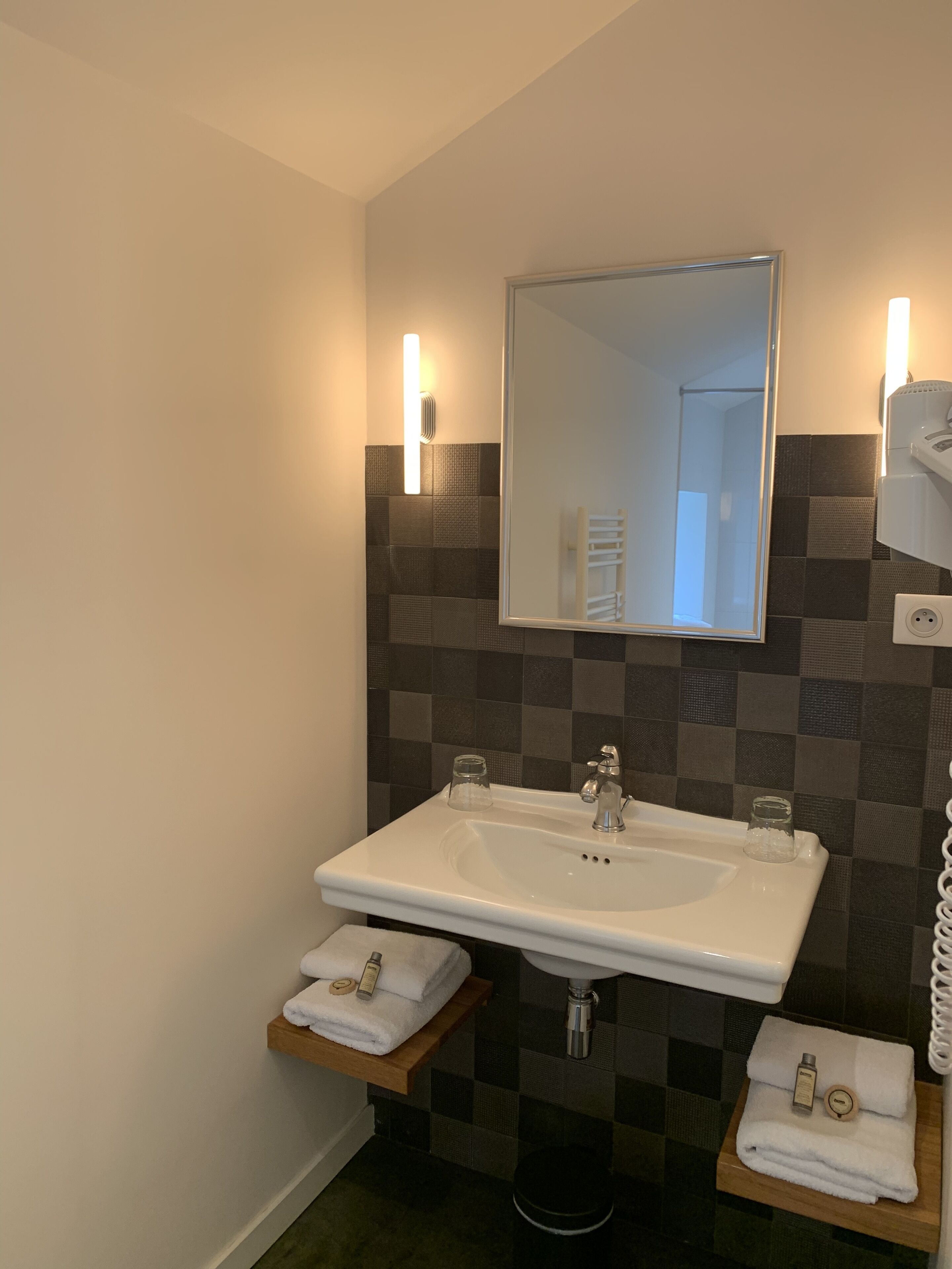 Un baño con un lavamanos blanco, dos toalleros y un espejo.