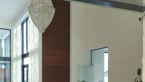 A modern reception area with a wooden reception desk, a large chandelier, and a view of the interior space. - Orexus Tower (Tbilisi)