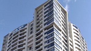A tall, modern building with multiple balconies and a clear sky. - Orexus Tower (Tbilisi)