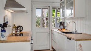 A compact kitchen with white cabinetry, a built-in oven, a coffee maker, and a window with a view of trees. - Awesome home in Malling with WiFi (Malling)