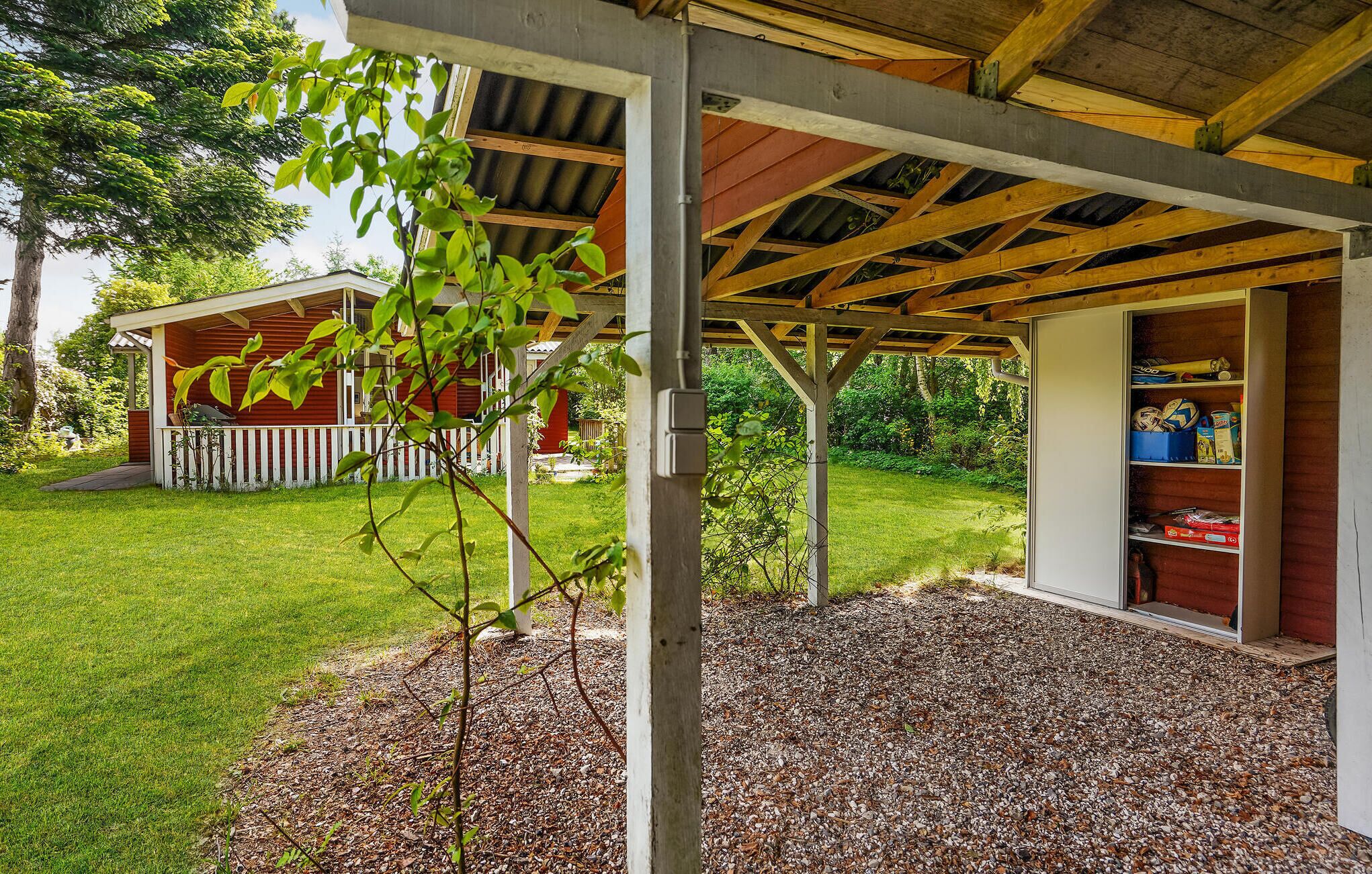 Un espace extérieur abrité doté d’une structure en bois, d’un petit abri de jardin et d’un chemin de gravier.