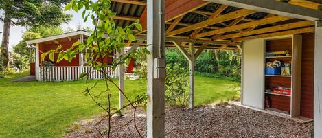 Un espace extérieur abrité doté d’une structure en bois, d’un petit abri de jardin et d’un chemin de gravier.