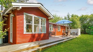 A red wooden house with a deck, a table with chairs, and a blue umbrella. - Awesome home in Malling with WiFi (Malling)