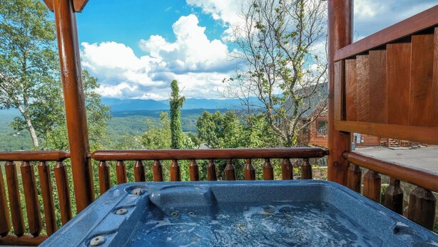 A hot tub on a wooden deck with a view of mountains and trees. - Scenic Sunrise - Mountain Views + Community Pool Access + Outdoor Hot Tub (Sevierville)