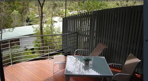 A balcony with a table and chairs, a railing, and a view of trees and a building in the background. - Sun-Set Satinay at Kingfisher Bay Resort (Kingfisher Bay)