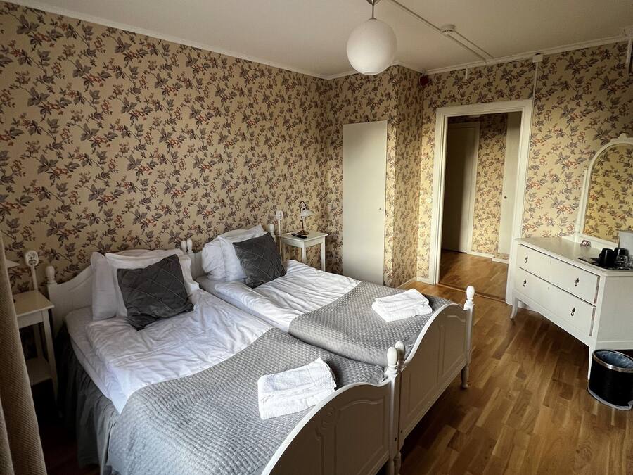 Un dormitorio con dos camas, un aparador, un espejo y una mesita.