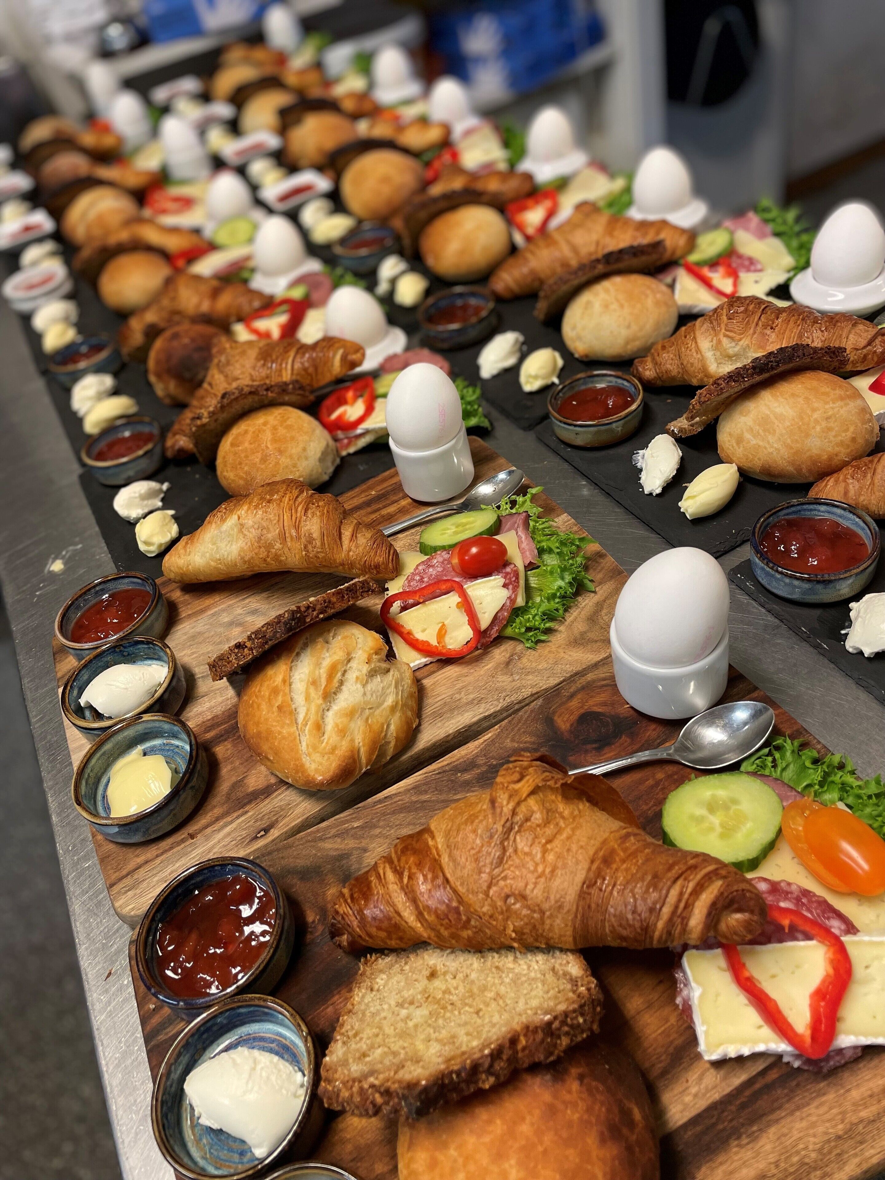 Une table de buffet proposant divers aliments, notamment des croissants, du pain, du fromage et des légumes.