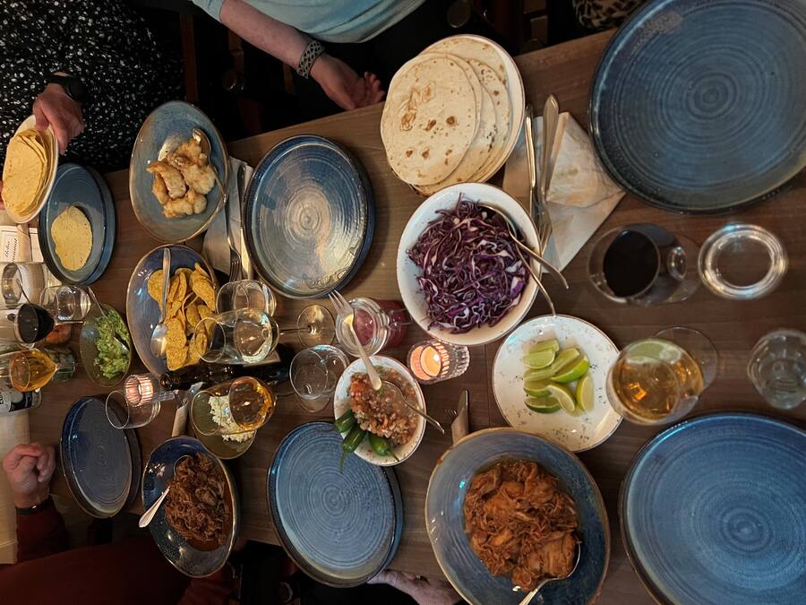 A table with various dishes, including tortillas, a bowl of red cabbage, and a plate of chicken.
