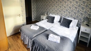 Un dormitorio con una cama doble, dos mesitas de noche, un buró, una silla y una puerta.