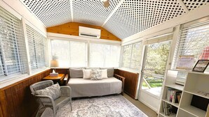 Een gezellige kamer met een bed, een stoel, een klein tafeltje en een boekenplank.