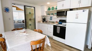 Une cuisine de taille réduite avec des meubles blancs, un four à micro-ondes, une cuisinière et un réfrigérateur.