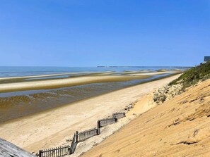 Une plage avec une promenade en bois et une clôture menant à un bâtiment.