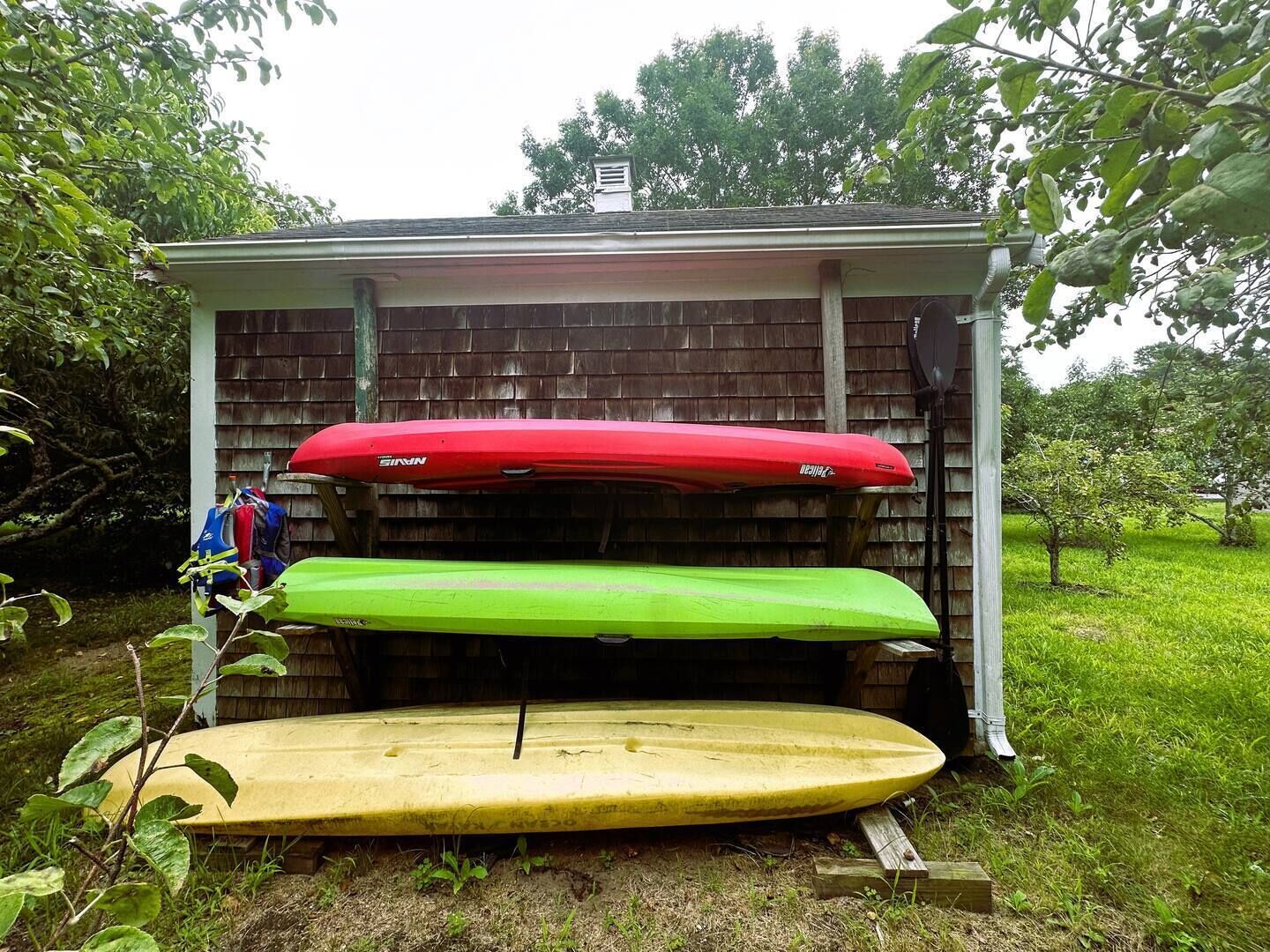 Un petit abri de jardin dans lequel sont rangés trois kayaks.