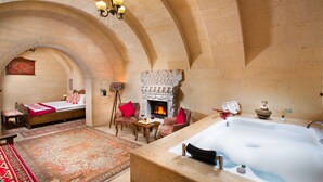 A luxurious room with a large bathtub, a fireplace, and a cozy seating area with a rug and pillows. - Simera In Cappadocia - Special Class (Nevsehir)