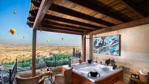 A room with a large wooden bathtub, a dining table with chairs, and a view of the landscape. - Simera In Cappadocia - Special Class (Nevsehir)