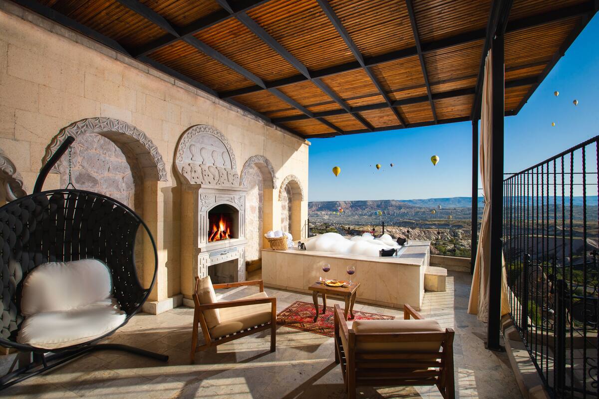 A terrace with a stone fireplace, seating, and a view of the landscape.