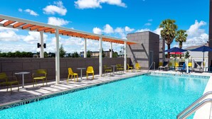 A swimming pool with yellow chairs and a covered seating area. - Home2 Suites by Hilton Wildwood the Villages (Wildwood)