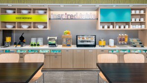 A breakfast area with a sign reading "inspired table," a coffee machine, and a display of pastries. - Home2 Suites by Hilton Wildwood the Villages (Wildwood)