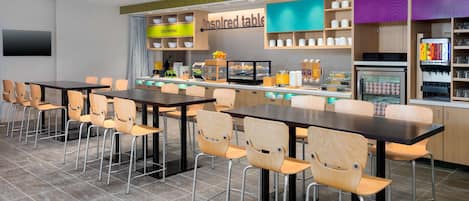 A modern restaurant with a long counter, multiple tables, and chairs.