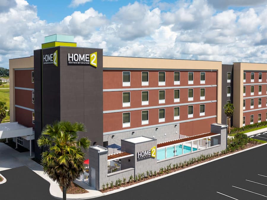 A multi-story hotel with a pool area, a covered patio, and a parking lot.