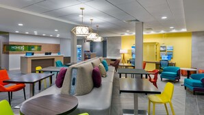 A hotel lobby with a reception desk, seating areas, and a vending machine. - Home2 Suites by Hilton Wildwood the Villages (Wildwood)