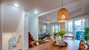 Uma sala de jantar com mesa de madeira, cadeiras e luminária pendente.
